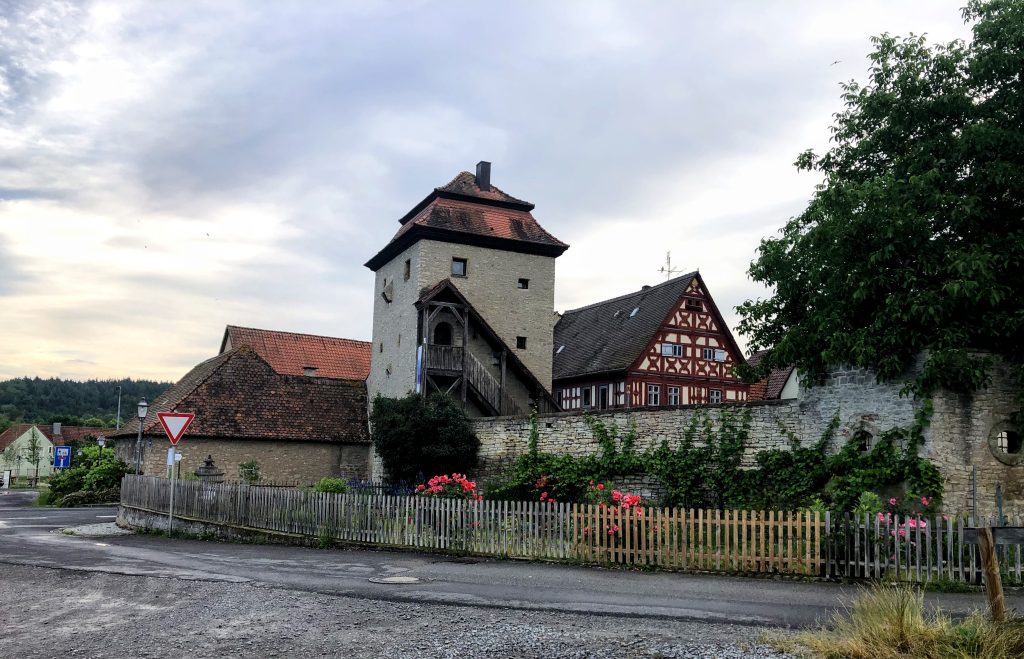 Medieval city tower and city wall in a small Bavarian Village with a red and white half-timbered house 